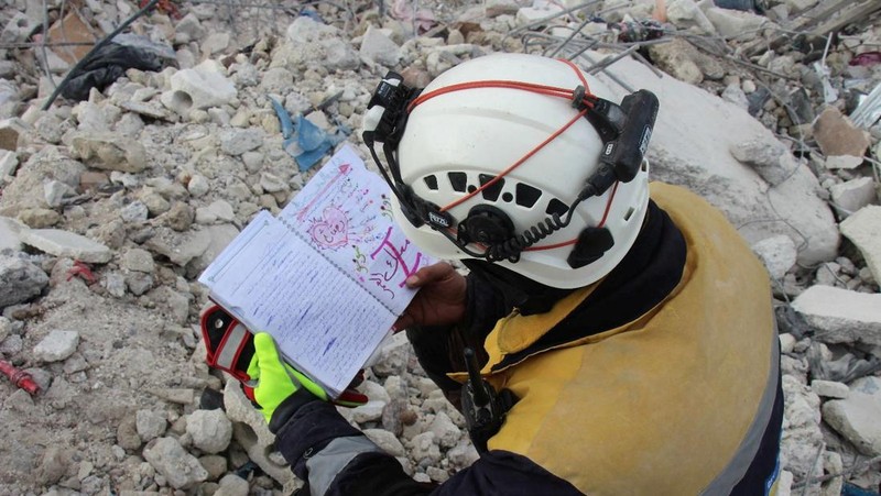 Seorang anggota White Helmets melihat buku catatan yang ditemukan di sebuah bangunan yang rusak, setelah gempa bumi, di kota Jandaris yang dikuasai pemberontak, Suriah, 10 Februari 2023. (White Helmets/Handout via REUTERS)