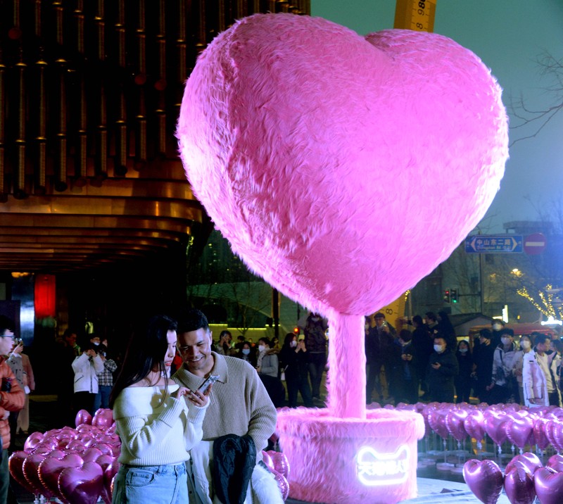 Warga menyaksikan instalasi dekoratif berbentuk hati setinggi 5 meter yang dikelilingi balon berbentuk hati di Bund Finance Center sebelum Hari Valentine pada 12 Februari 2023 di Shanghai, China. (Photo by VCG/VCG via Getty Images)