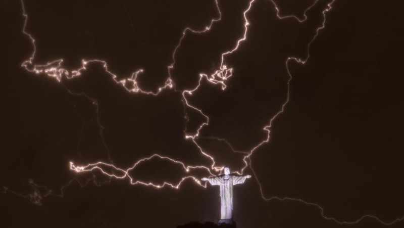 A lightning flashes over the statue of Christ the Redeemer on top of the Corcovado hill in Rio de Janeiro, Brazil, on January 16, 2014.  AFP PHOTO / YASUYOSHI CHIBA        (Photo credit should read YASUYOSHI CHIBA/AFP via Getty Images)
