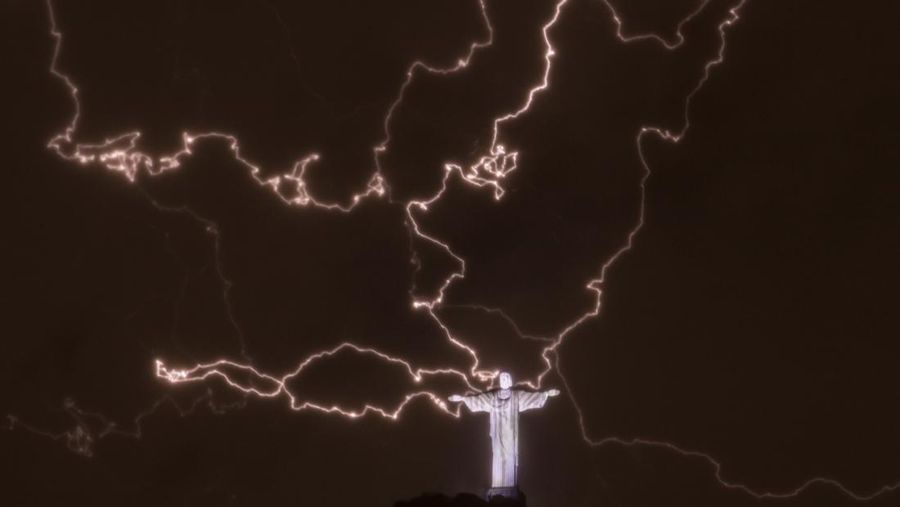 A lightning flashes over the statue of Christ the Redeemer on top of the Corcovado hill in Rio de Janeiro, Brazil, on January 16, 2014. AFP PHOTO / YASUYOSHI CHIBA (Photo credit should read YASUYOSHI CHIBA/AFP via Getty Images)