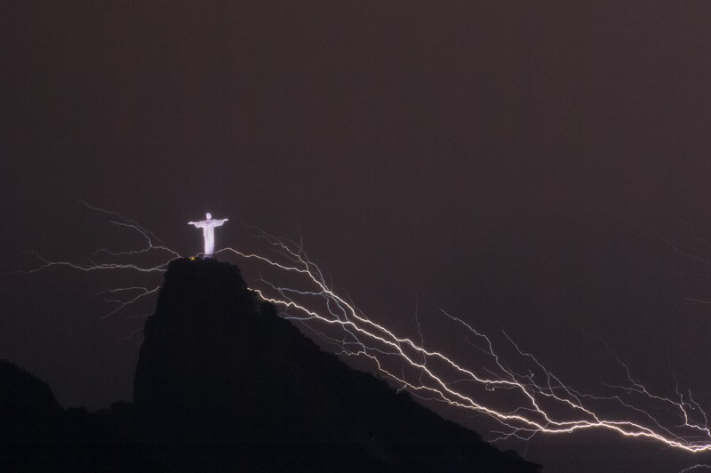 A lightning flashes over the statue of Christ the Redeemer on top of the Corcovado hill in Rio de Janeiro, Brazil, on January 16, 2014.  AFP PHOTO / YASUYOSHI CHIBA        (Photo credit should read YASUYOSHI CHIBA/AFP via Getty Images)