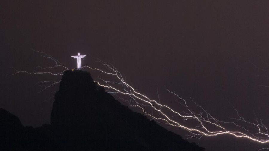 A lightning flashes over the statue of Christ the Redeemer on top of the Corcovado hill in Rio de Janeiro, Brazil, on January 16, 2014.  AFP PHOTO / YASUYOSHI CHIBA        (Photo credit should read YASUYOSHI CHIBA/AFP via Getty Images)