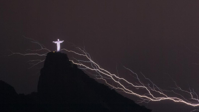 A lightning flashes over the statue of Christ the Redeemer on top of the Corcovado hill in Rio de Janeiro, Brazil, on January 16, 2014.  AFP PHOTO / YASUYOSHI CHIBA        (Photo credit should read YASUYOSHI CHIBA/AFP via Getty Images)