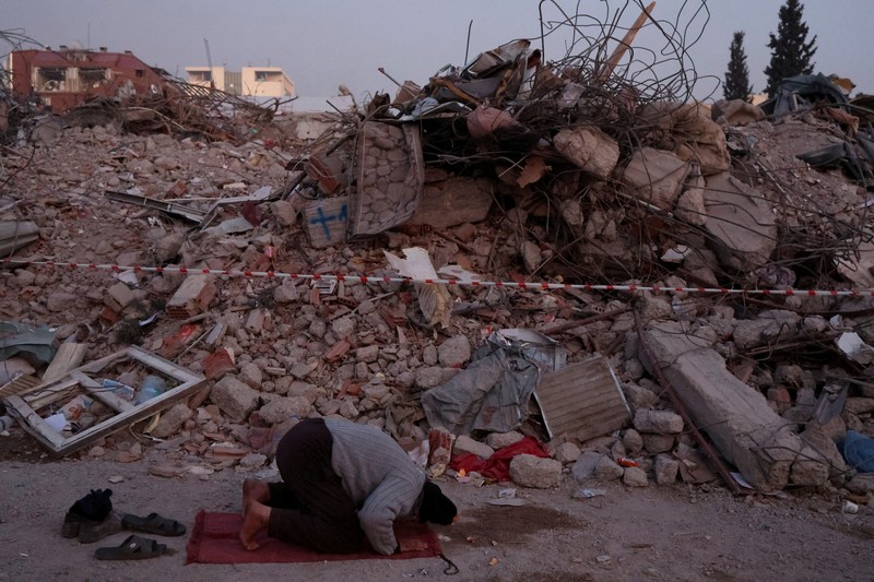 A man prays near the rubble of destroyed homes, in the aftermath of a deadly earthquake in Kahramanmaras, Turkey February 14, 2023. REUTERS/Nir Elias     TPX IMAGES OF THE DAY