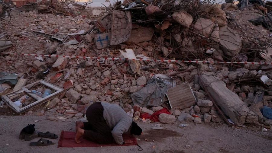 A man prays near the rubble of destroyed homes, in the aftermath of a deadly earthquake in Kahramanmaras, Turkey February 14, 2023. REUTERS/Nir Elias     TPX IMAGES OF THE DAY