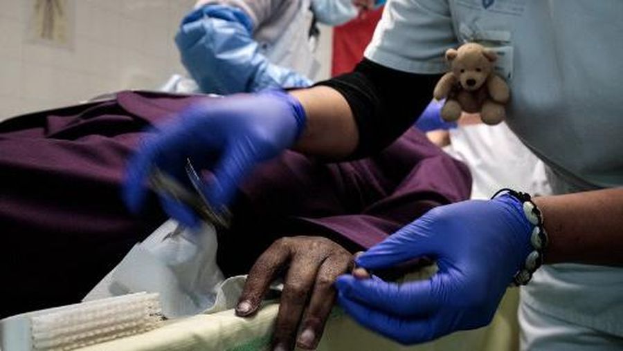 Members of the medical staff cut the nails and prepare the body of a deceased patient, in order to present it to family members, in the mortuary room at the Bichat Claude Bernard Hospital AP-HP (Assistance Publique - Hopitaux de Paris), in Paris, on January 29, 2021. (Photo by JOEL SAGET / AFP)