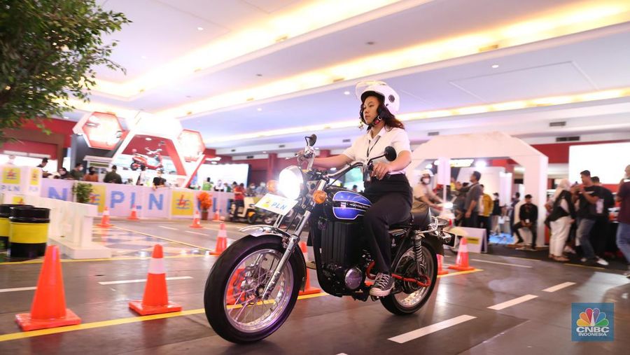 Pengunjung melihat motor lawas yang di konversi menjadi motor listrik pada booth PLN dalam ajang pameran otomotif Indonesia International Motor Show (IIMS) 2023 pada Sabtu (18/2/2023). (CNBC Indonesia/Tias Budiarto)