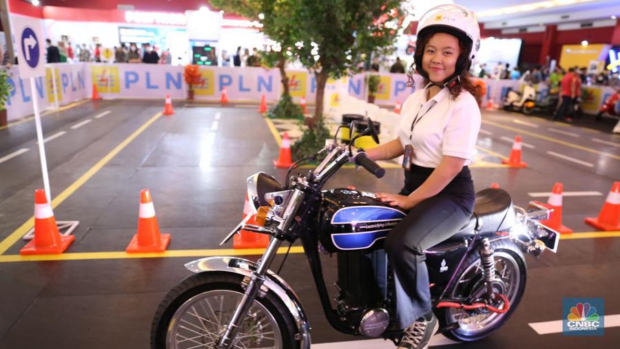 Pengunjung melihat motor lawas yang di konversi menjadi motor listrik pada booth PLN dalam ajang pameran otomotif Indonesia International Motor Show (IIMS) 2023 pada Sabtu (18/2/2023). (CNBC Indonesia/Tias Budiarto)