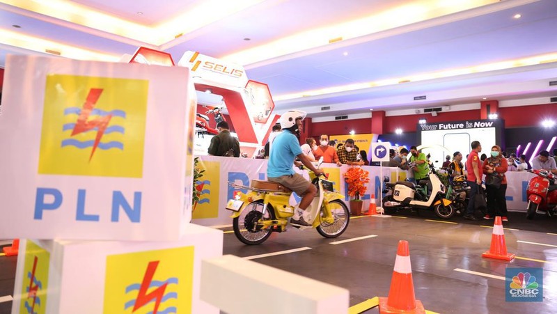 Pengunjung melihat motor lawas yang di konversi menjadi motor listrik pada booth PLN dalam ajang pameran otomotif Indonesia International Motor Show (IIMS) 2023 pada Sabtu (18/2/2023). (CNBC Indonesia/Tias Budiarto)