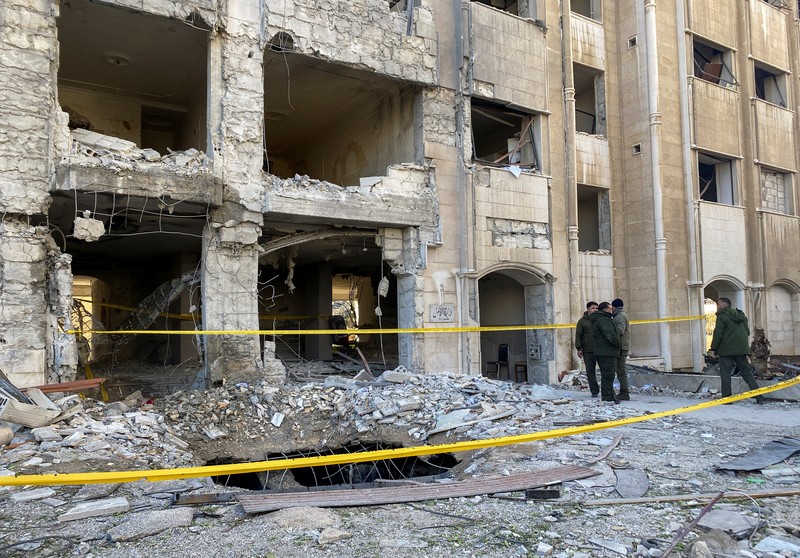 Police officers stand near a damaged building at the site of a rocket attack, in central Damascus' Kafr Sousa neighborhood, Syria, February 19, 2023. REUTERS/Firas Makdessi