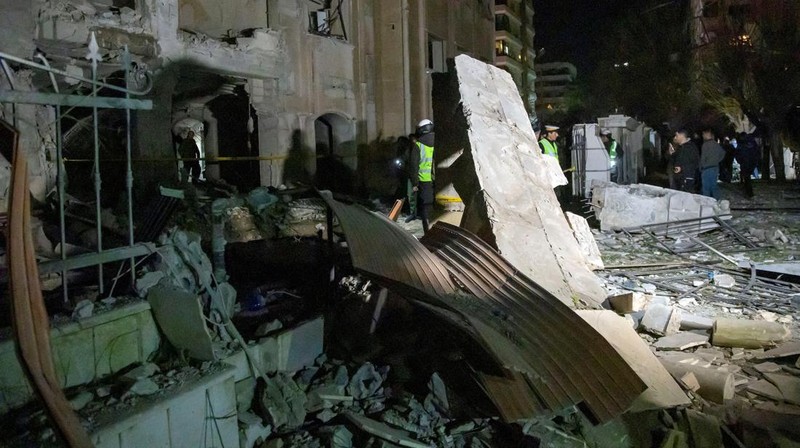 Police officers stand near a damaged building at the site of a rocket attack, in central Damascus' Kafr Sousa neighborhood, Syria, February 19, 2023. REUTERS/Firas Makdessi