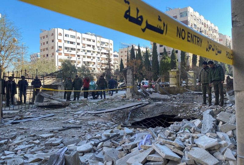 Police officers stand near a damaged building at the site of a rocket attack, in central Damascus' Kafr Sousa neighborhood, Syria, February 19, 2023. REUTERS/Firas Makdessi