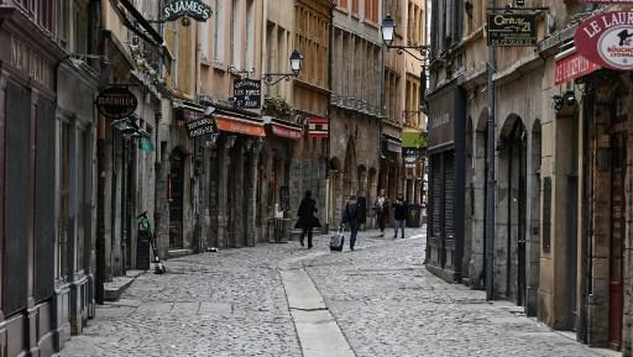 People walk past closed shops and restaurants in an empty street of the historic neighborhood in Lyon, on March 16, 2020 during a COVID-19 outbreak hitting Europe. - French president will speak on television at 8:00 (Paris time) on March 16, 2020 to announce new measures to fight the growing coronavirus epidemic, said the Elysee. The balance sheet of the epidemic climbed to 127 dead and 5,423 confirmed cases in France. (Photo by PHILIPPE DESMAZES / AFP)