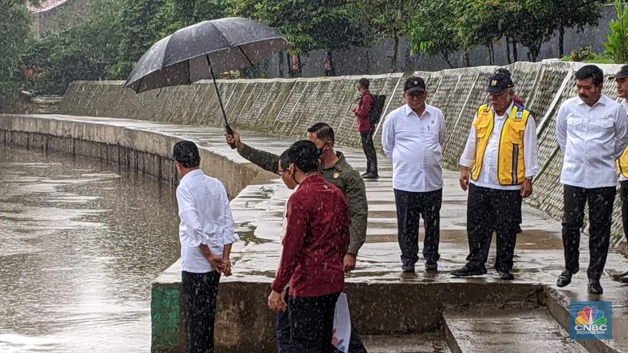 Di tengah hujan lebat Presiden Joko Widodo melakukan peninjauan titik normalisasi kali Ciliwung, yang berada di Jalan Inspeksi Ciliwung, Jakarta Selatan, pada Selasa (21/2/2023). (CNBC Indonesia/Emir Yanwardhana)