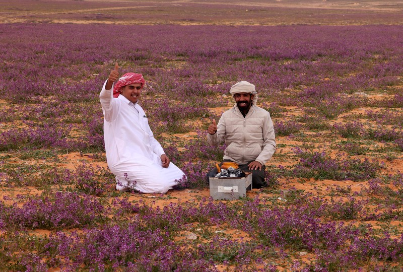 Seorang warga mengambil foto bukit yang menghijau setelah hujan deras di Mekkah, Arab Saudi pada 16 Januari 2023. (Photo by Hani Alshaer/Anadolu Agency via Getty Images)