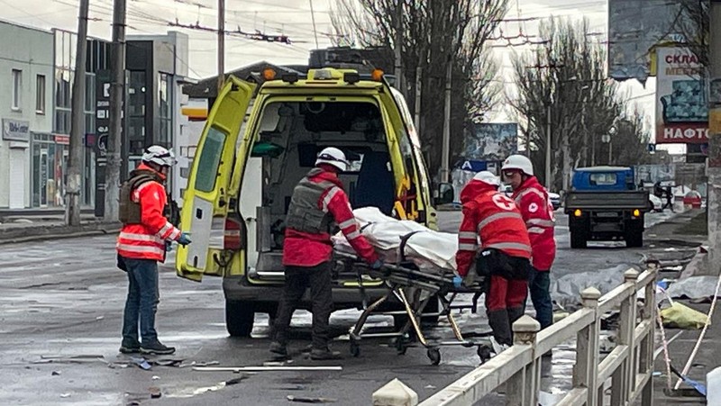 Pekerja darurat merawat korban setelah serangan roket BM-21 meledakkan halte bus di Kherson, Ukraina pada 21 Februari 2023. (Vincenzo Circosta/Anadolu Agency via Getty Images)