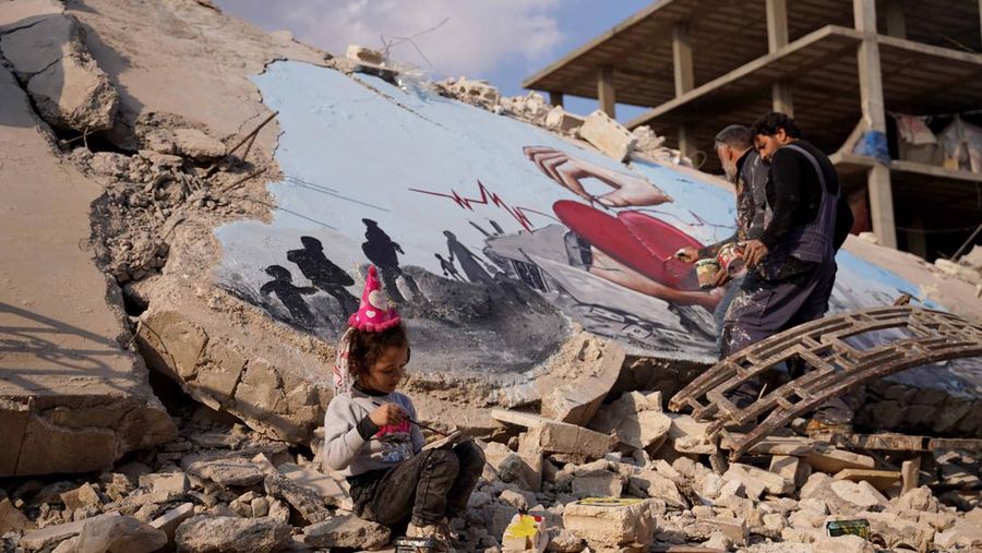 Seniman grafiti Suriah Aziz Asmar, Salam Hamid dan Muhammad Enis Hamdun melukis perjuangan gempa bumi di atas puing-puing bangunan yang runtuh di Jindires, sebuah distrik di Afrin yang terkena dampak gempa bumi Turkiye-Suriah 06 Februari di Aleppo, Suriah pada 22 Februari, 2023. (Omer Alven/Anadolu Agency via Getty Images)