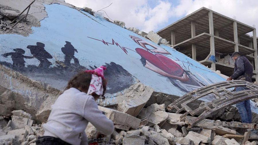 Seniman grafiti Suriah Aziz Asmar, Salam Hamid dan Muhammad Enis Hamdun melukis perjuangan gempa bumi di atas puing-puing bangunan yang runtuh di Jindires, sebuah distrik di Afrin yang terkena dampak gempa bumi Turkiye-Suriah 06 Februari di Aleppo, Suriah pada 22 Februari, 2023. (Omer Alven/Anadolu Agency via Getty Images)