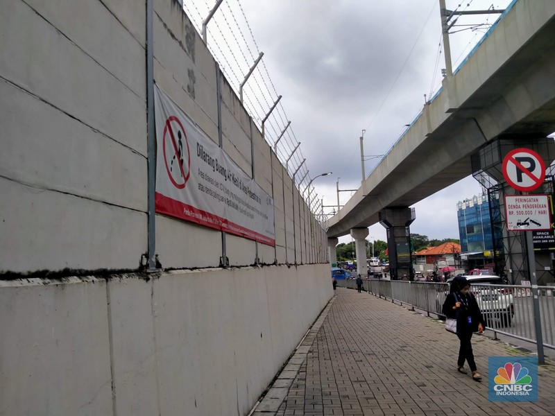 Warga melewati spanduk larangan encing di pinggir Jakarta, 'Kena' Rp 20 Juta di kawasan Lebak Bulus, Jakarta, Kamis (23/2/2023). (CNBC Indonesia/Suhendra)