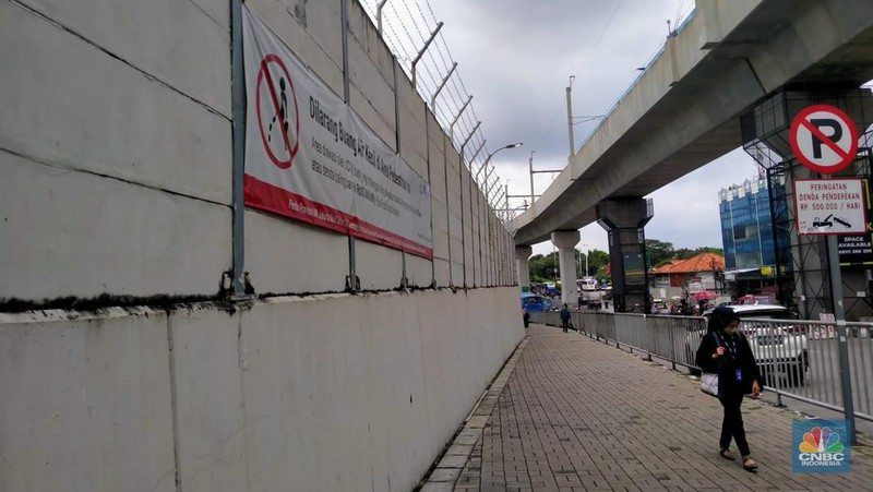 Warga melewati spanduk larangan encing di pinggir Jakarta, 'Kena' Rp 20 Juta di kawasan Lebak Bulus, Jakarta, Kamis (23/2/2023). (CNBC Indonesia/Suhendra)