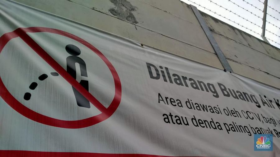 Warga melewati spanduk larangan encing di pinggir Jakarta, 'Kena' Rp 20 Juta di kawasan Lebak Bulus, Jakarta, Kamis (23/2/2023). (CNBC Indonesia/Suhendra)