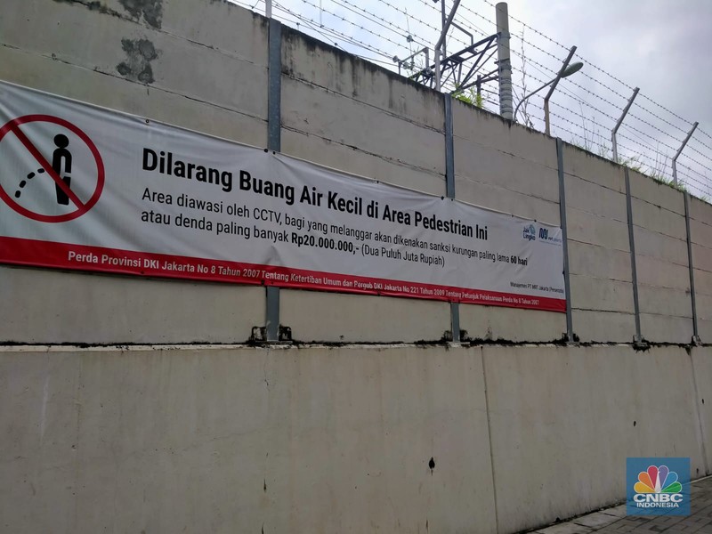 Warga melewati spanduk larangan encing di pinggir Jakarta, 'Kena' Rp 20 Juta di kawasan Lebak Bulus, Jakarta, Kamis (23/2/2023). (CNBC Indonesia/Suhendra)