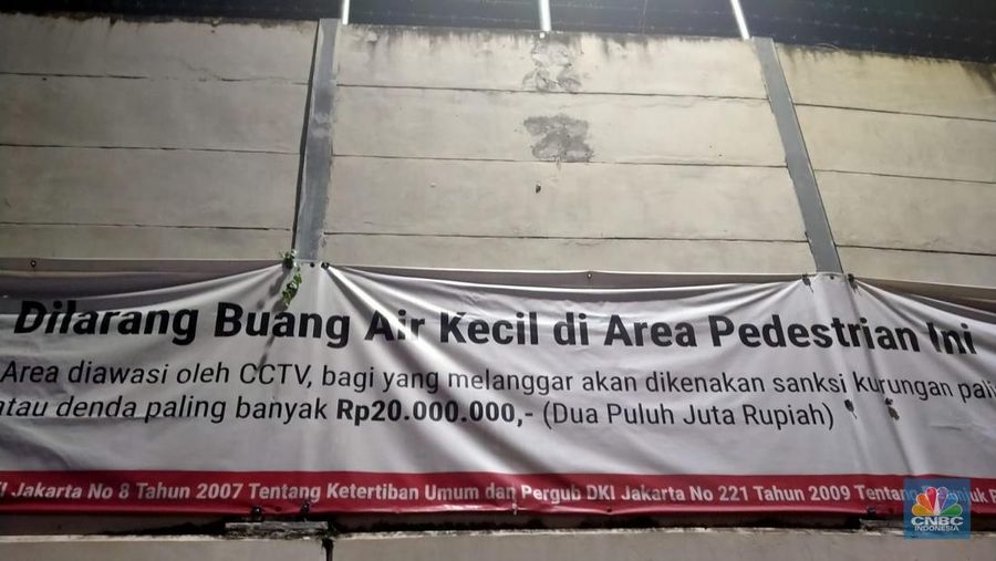 Warga melewati spanduk larangan encing di pinggir Jakarta, 'Kena' Rp 20 Juta di kawasan Lebak Bulus, Jakarta, Kamis (23/2/2023). (CNBC Indonesia/Suhendra)