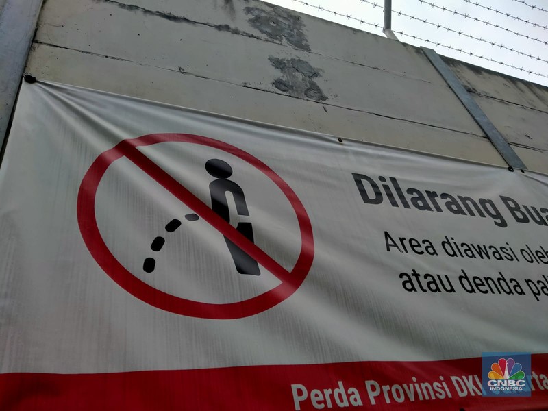 Warga melewati spanduk larangan encing di pinggir Jakarta, 'Kena' Rp 20 Juta di kawasan Lebak Bulus, Jakarta, Kamis (23/2/2023). (CNBC Indonesia/Suhendra)