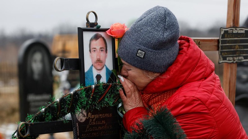 Istri Natalia bereaksi di makam Vasyl Maznichenko, penduduk lokal yang dibunuh oleh tentara Rusia selama pendudukan kota Bucha, pada hari peringatan pertama serangan Rusia di Ukraina, di pemakaman kota, di luar Kyiv, Ukraina 24 Februari 2023. (REUTERS/Valentyn Ogirenko)