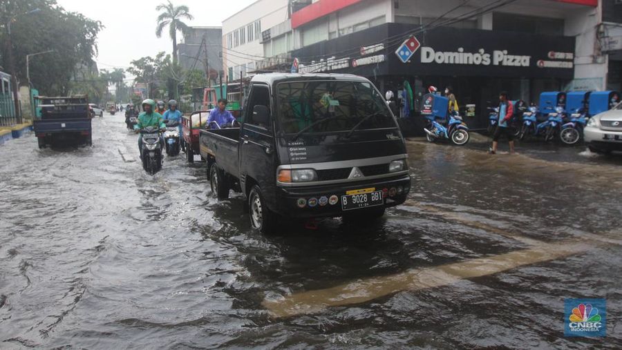 Pengendara melintasi genangan di Kawasan Green Garden, Kedoya, Jakarta Barat, Jumat (24/2/2023). (CNBC Indonesia/ Muhammad Sabki)