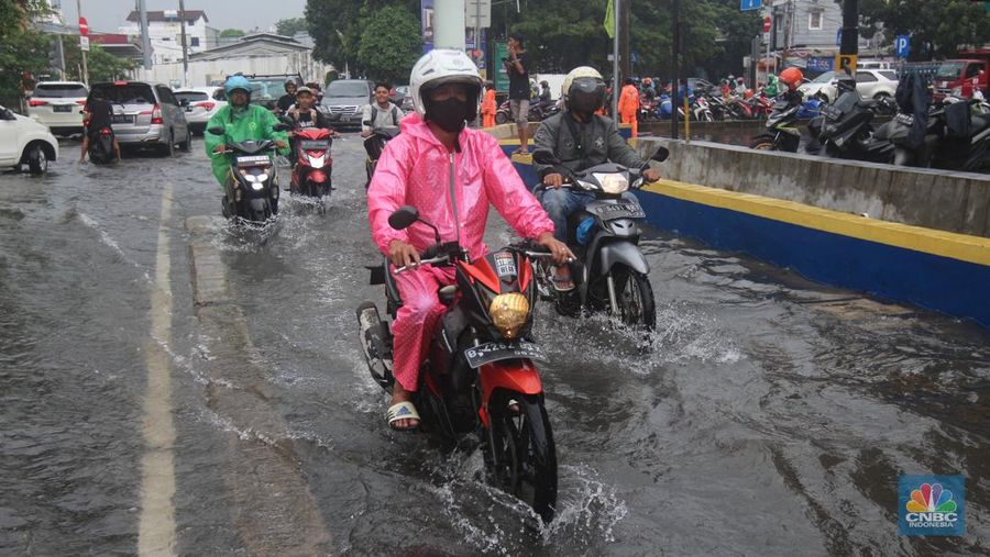 Pengendara melintasi genangan di Kawasan Green Garden, Kedoya, Jakarta Barat, Jumat (24/2/2023). (CNBC Indonesia/ Muhammad Sabki)
