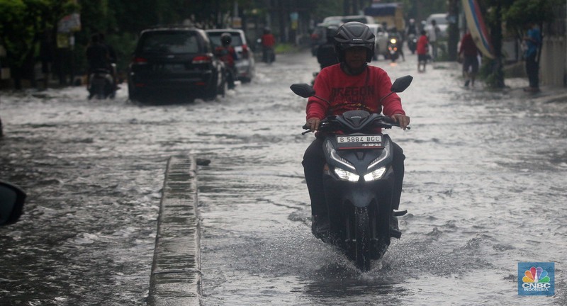 Pengendara melintasi genangan di Kawasan Green Garden, Kedoya, Jakarta Barat, Jumat (24/2/2023). (CNBC Indonesia/ Muhammad Sabki)