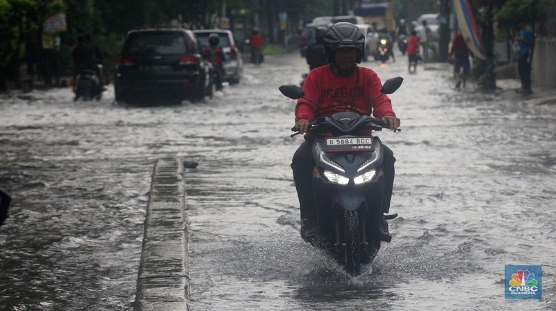 Pengendara melintasi genangan di Kawasan Green Garden, Kedoya, Jakarta Barat, Jumat (24/2/2023). (CNBC Indonesia/ Muhammad Sabki)