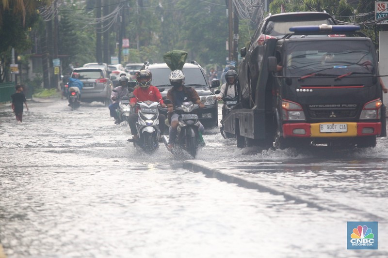 Pengendara melintasi genangan di Kawasan Green Garden, Kedoya, Jakarta Barat, Jumat (24/2/2023). (CNBC Indonesia/ Muhammad Sabki)