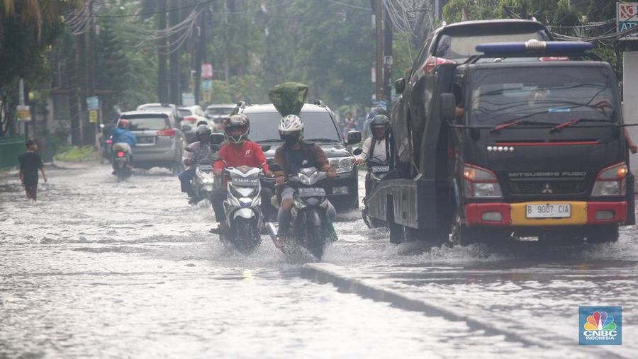 Pengendara melintasi genangan di Kawasan Green Garden, Kedoya, Jakarta Barat, Jumat (24/2/2023). (CNBC Indonesia/ Muhammad Sabki)