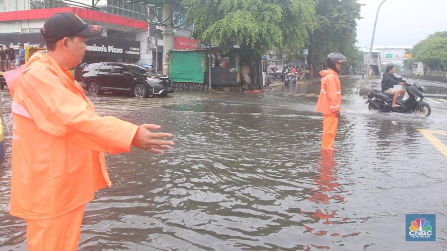 Pengendara melintasi genangan di Kawasan Green Garden, Kedoya, Jakarta Barat, Jumat (24/2/2023). (CNBC Indonesia/ Muhammad Sabki)