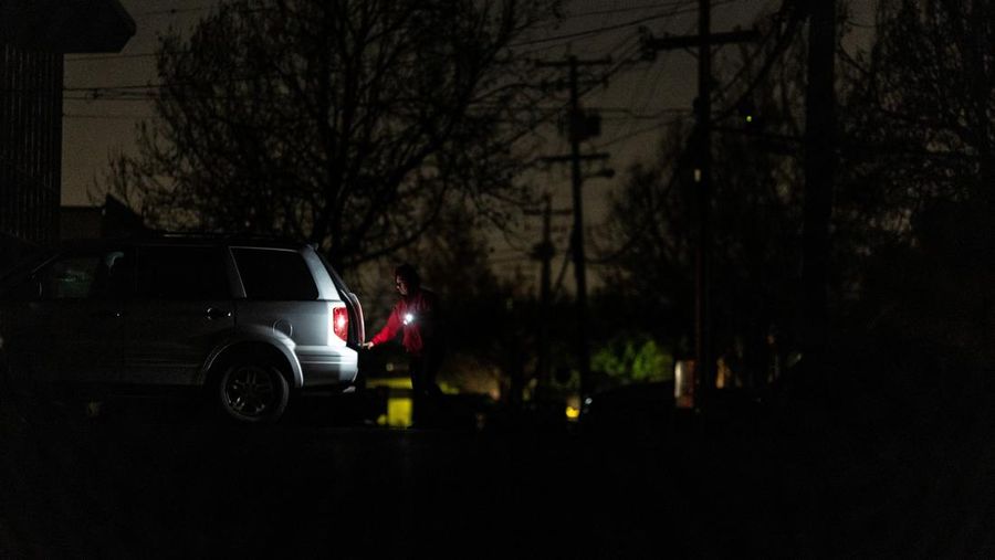 Seorang pria berjalan di sepanjang jalan kosong dalam kegelapan, menyusul badai musim dingin yang besar yang meninggalkan rumah dan bisnis tanpa listrik, di Menlo Park, California A.S., 21 Februari 2023. (REUTERS/ Carlos Barria)