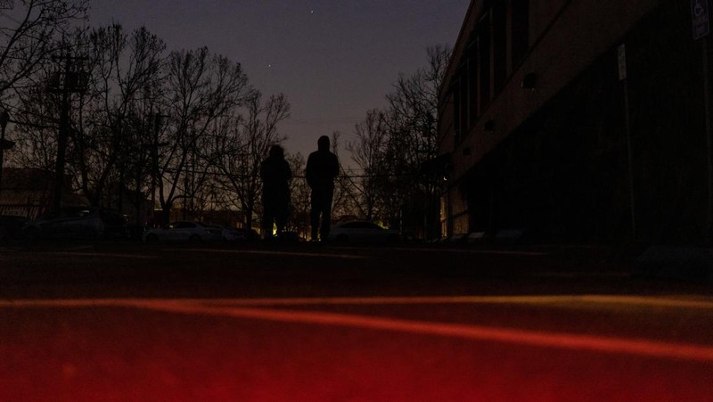 Seorang pria berjalan di sepanjang jalan kosong dalam kegelapan, menyusul badai musim dingin yang besar yang meninggalkan rumah dan bisnis tanpa listrik, di Menlo Park, California A.S., 21 Februari 2023. (REUTERS/ Carlos Barria)