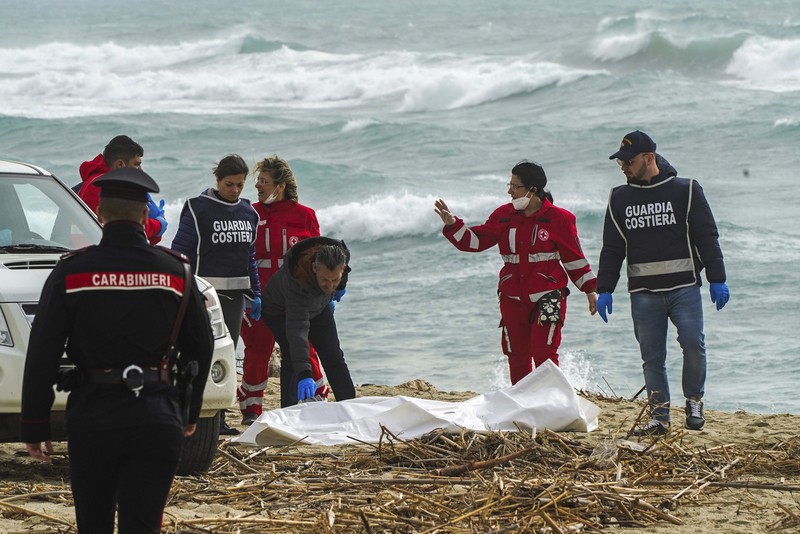 APTOPIX Migration Italy Italian Red Cross volunteers and coast guards recover a body after a migrant boat broke apart in rough seas, at a beach near Cutro, southern Italy, Sunday, Feb. 26, 2023. Rescue officials say an undetermined number of migrants have died and dozens have been rescued after their boat broke apart off southern Italy.(Antonino Durso/LaPresse via AP)