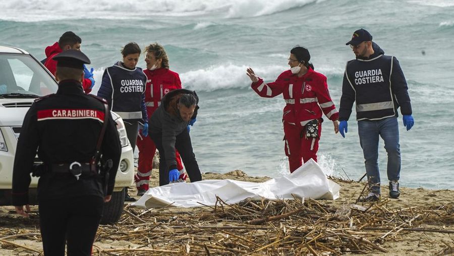 Italian Red Cross volunteers and coast guards recover a body after a migrant boat broke apart in rough seas, at a beach near Cutro, southern Italy, Sunday, Feb. 26, 2023. Rescue officials say an undetermined number of migrants have died and dozens have been rescued after their boat broke apart off southern Italy.(Antonino Durso/LaPresse via AP)
