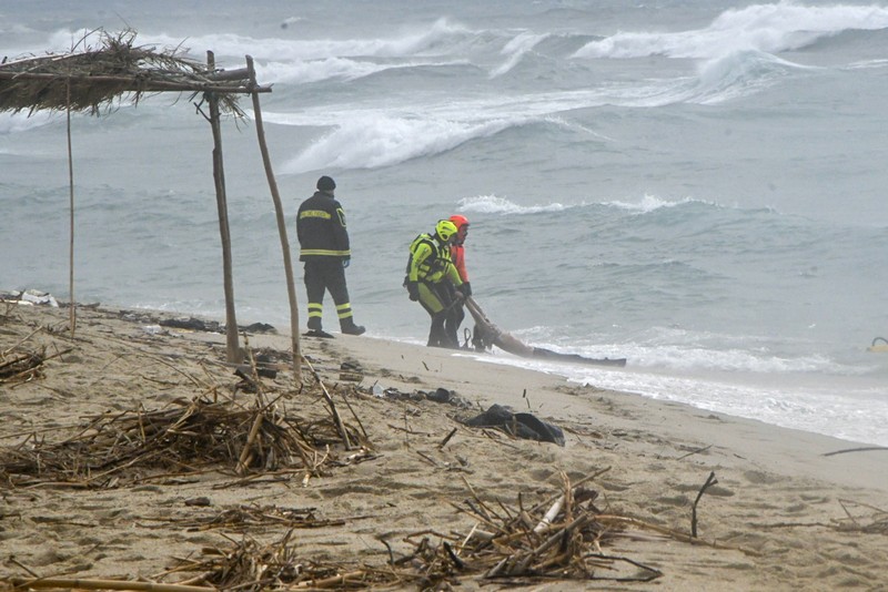 APTOPIX Migration Italy Italian Red Cross volunteers and coast guards recover a body after a migrant boat broke apart in rough seas, at a beach near Cutro, southern Italy, Sunday, Feb. 26, 2023. Rescue officials say an undetermined number of migrants have died and dozens have been rescued after their boat broke apart off southern Italy.(Antonino Durso/LaPresse via AP)