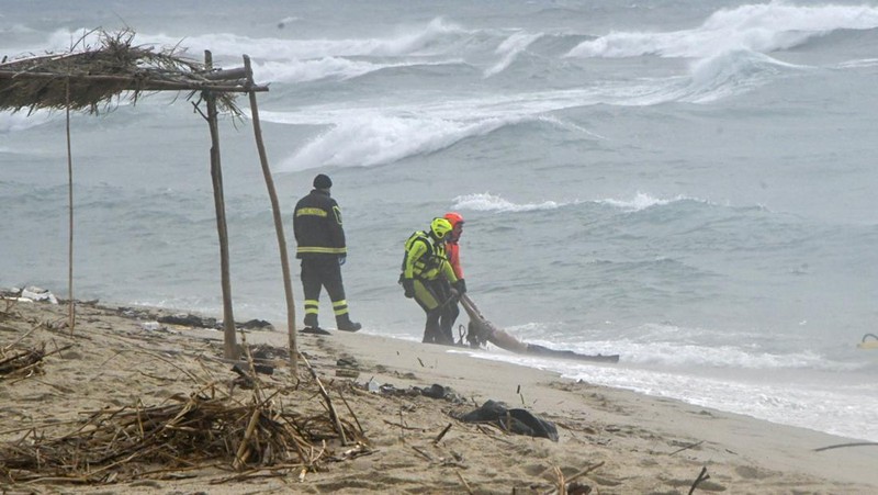 Italian Red Cross volunteers and coast guards recover a body after a migrant boat broke apart in rough seas, at a beach near Cutro, southern Italy, Sunday, Feb. 26, 2023. Rescue officials say an undetermined number of migrants have died and dozens have been rescued after their boat broke apart off southern Italy.(Antonino Durso/LaPresse via AP)