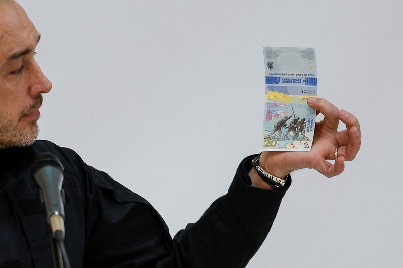 Gubernur Bank Nasional Ukraina Andriy Pyshnyi memegang uang kertas yang didedikasikan untuk peringatan satu tahun invasi Rusia di Ukraina, selama presentasi di Kyiv, Ukraina 23 Februari 2023. (REUTERS/Valentyn Ogirenko)