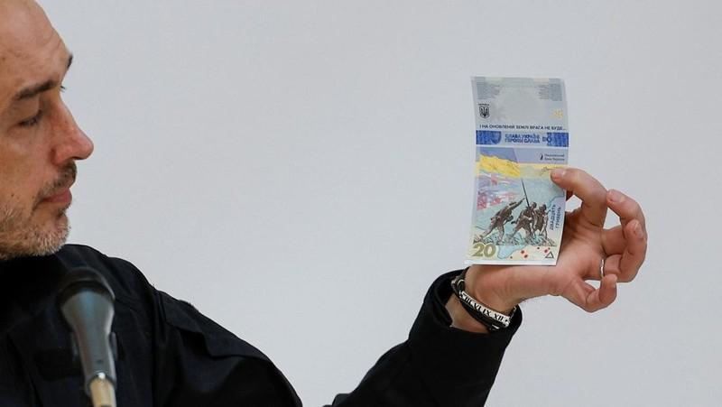 Gubernur Bank Nasional Ukraina Andriy Pyshnyi memegang uang kertas yang didedikasikan untuk peringatan satu tahun invasi Rusia di Ukraina, selama presentasi di Kyiv, Ukraina 23 Februari 2023. (REUTERS/Valentyn Ogirenko)