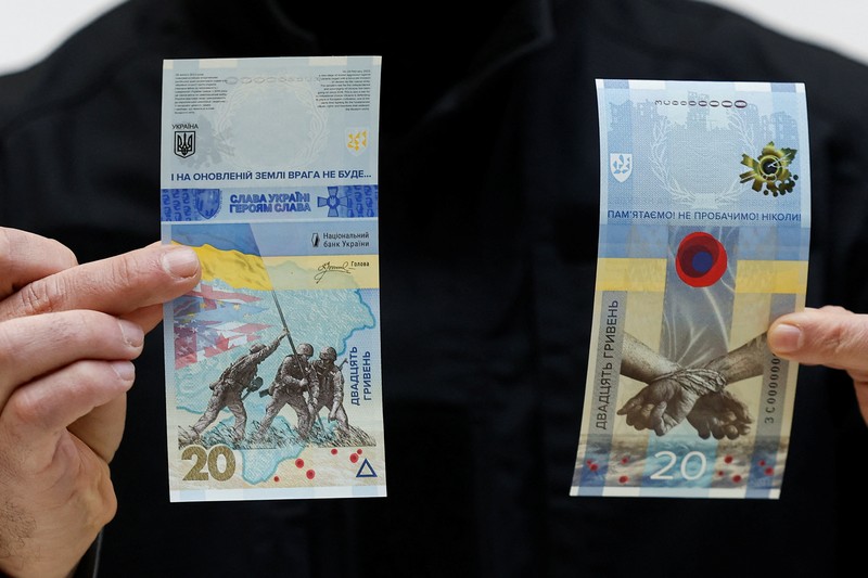Gubernur Bank Nasional Ukraina Andriy Pyshnyi memegang uang kertas yang didedikasikan untuk peringatan satu tahun invasi Rusia di Ukraina, selama presentasi di Kyiv, Ukraina 23 Februari 2023. (REUTERS/Valentyn Ogirenko)