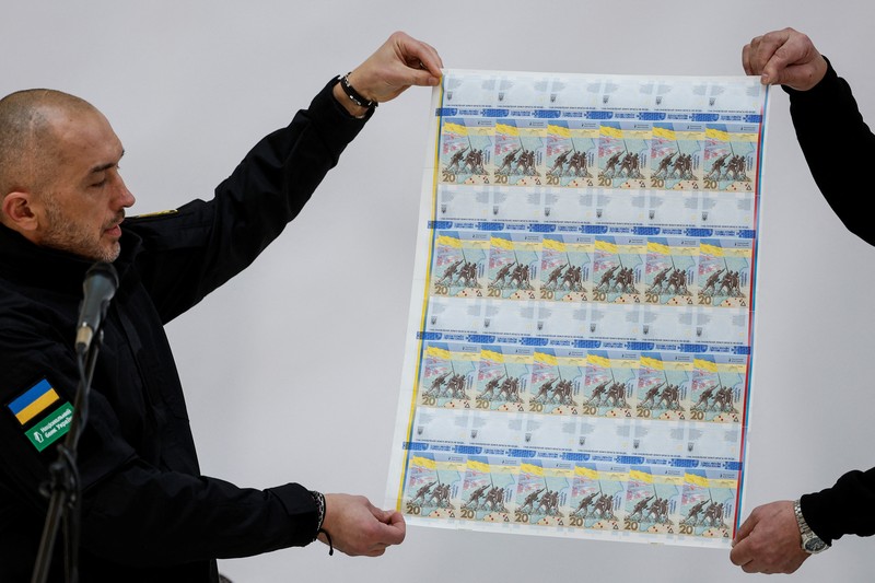 Gubernur Bank Nasional Ukraina Andriy Pyshnyi memegang uang kertas yang didedikasikan untuk peringatan satu tahun invasi Rusia di Ukraina, selama presentasi di Kyiv, Ukraina 23 Februari 2023. (REUTERS/Valentyn Ogirenko)