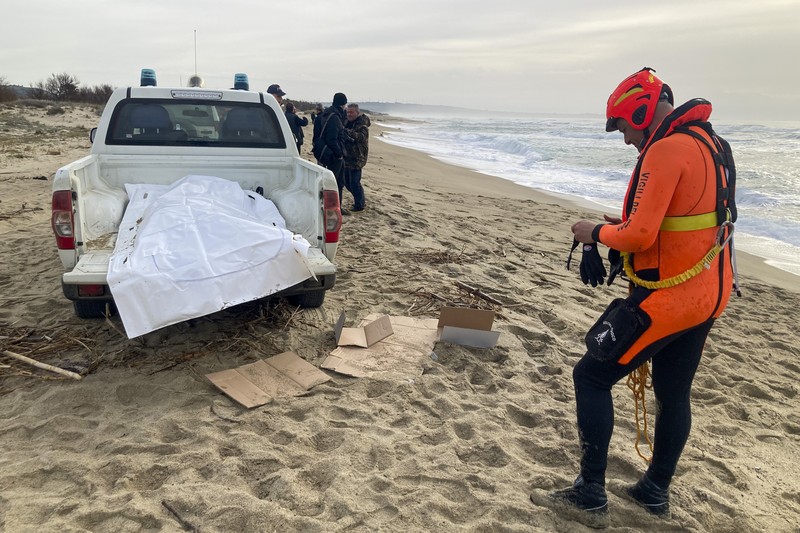 Italian Red Cross volunteers and coast guards recover a body after a migrant boat broke apart in rough seas, at a beach near Cutro, southern Italy, Sunday, Feb. 26, 2023. Rescue officials say an undetermined number of migrants have died and dozens have been rescued after their boat broke apart off southern Italy.(Antonino Durso/LaPresse via AP)