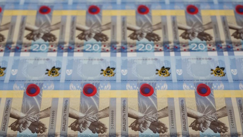 Gubernur Bank Nasional Ukraina Andriy Pyshnyi memegang uang kertas yang didedikasikan untuk peringatan satu tahun invasi Rusia di Ukraina, selama presentasi di Kyiv, Ukraina 23 Februari 2023. (REUTERS/Valentyn Ogirenko)