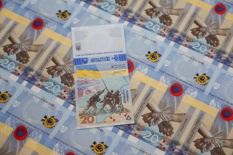 Gubernur Bank Nasional Ukraina Andriy Pyshnyi memegang uang kertas yang didedikasikan untuk peringatan satu tahun invasi Rusia di Ukraina, selama presentasi di Kyiv, Ukraina 23 Februari 2023. (REUTERS/Valentyn Ogirenko)