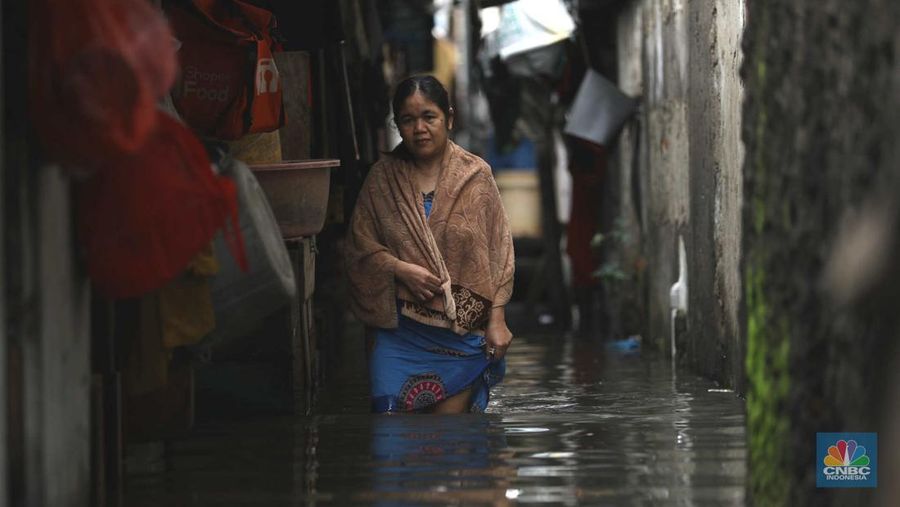 Warga beraktifitas saat banjir setinggi 60 cm menggenangi kawasan Pesing Koneng, Jakarta, Senin (27/2/2023). (CNBC Indonesia/Tri Susilo)
